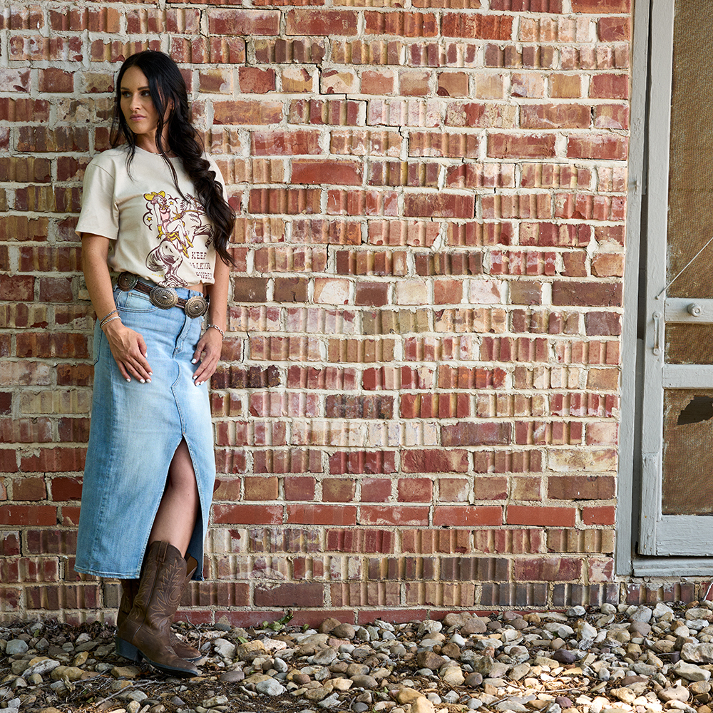 Woman wearing Ariat cowbgirl boots with denim skirt and t-shirt
