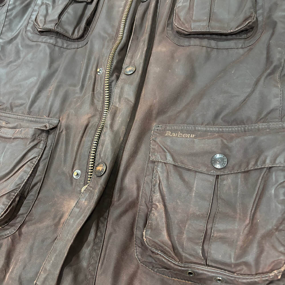 Close-up of a brown Barbour wax jacket showing faded areas across the shoulders, sleeves and chest.