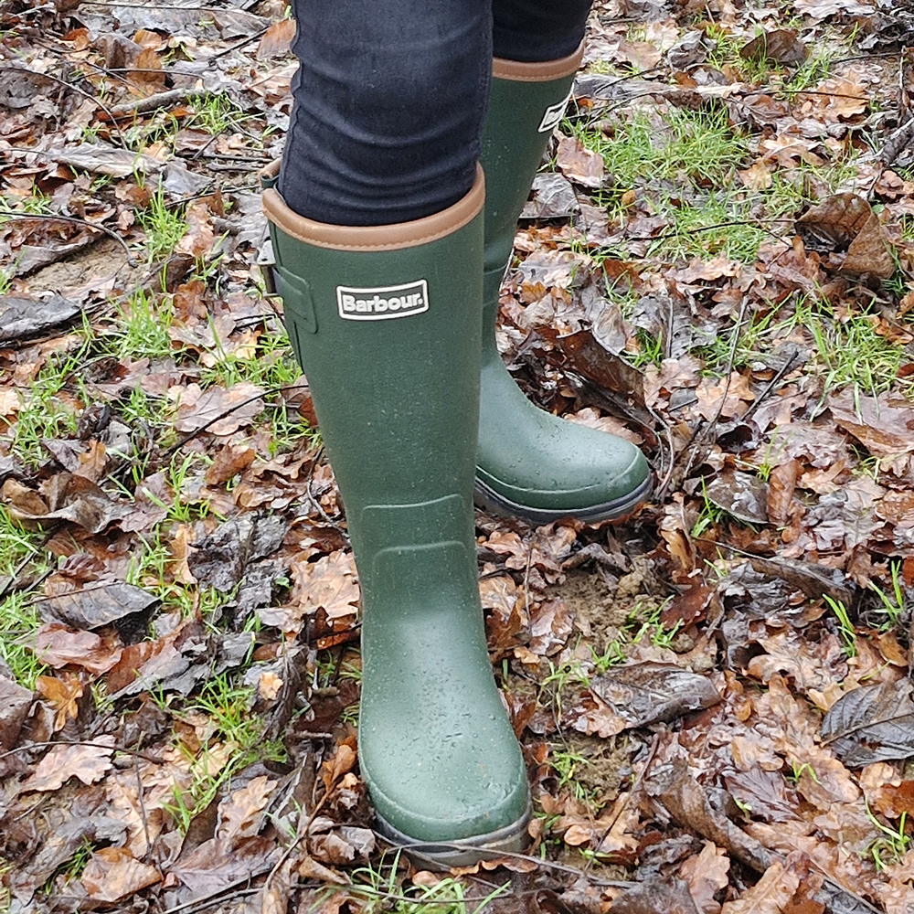 Close up of green Barbour Tempest Wellies in rainy muddy field