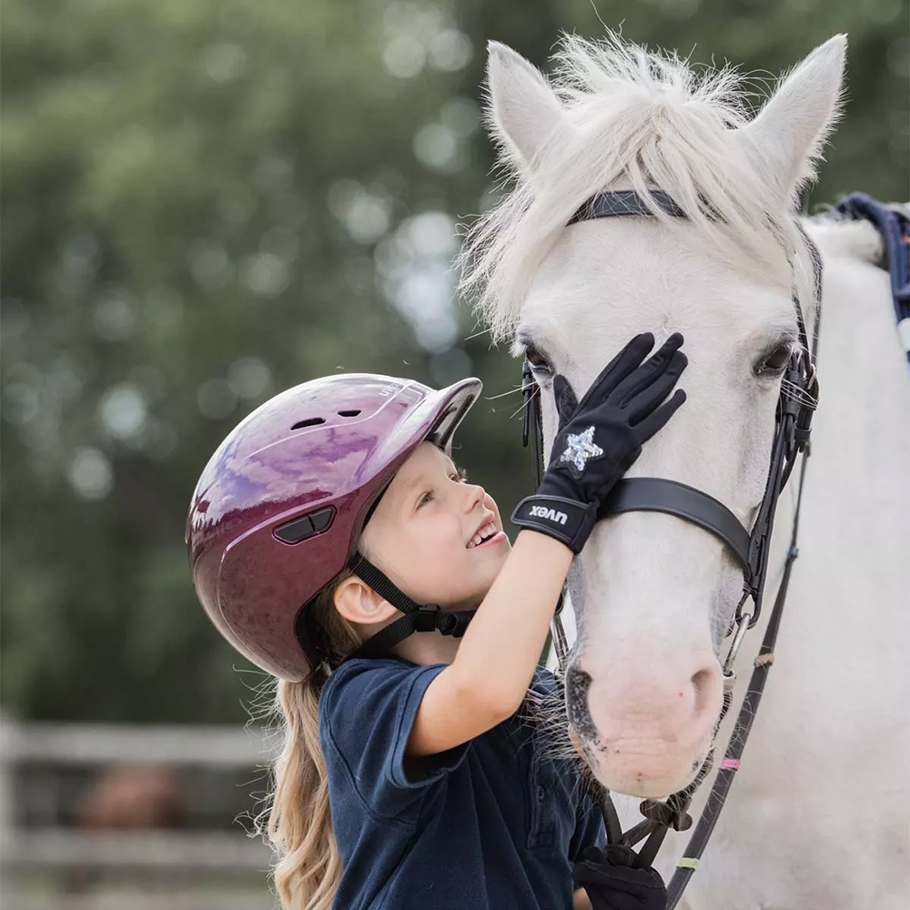 Child wearing correctly fitted horse riding helmet at a riding school