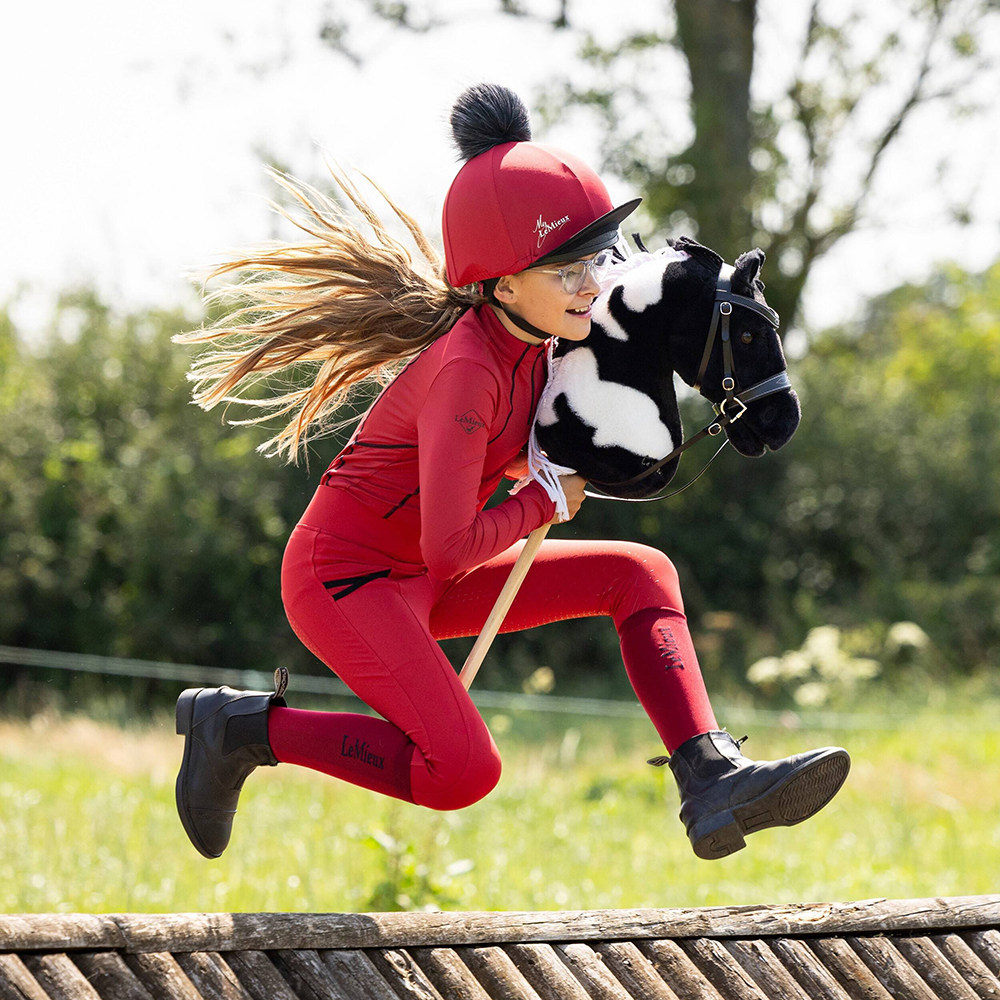 Child riding LeMieux Hobby Horse Razzle over a cross country jump