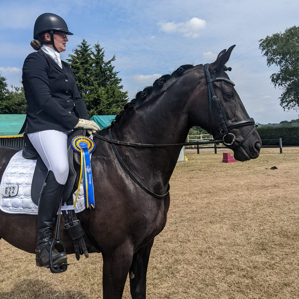 Woman riding horse at a dressage competition wearing the Mountain Horse Ladies Veganza Boots in Black