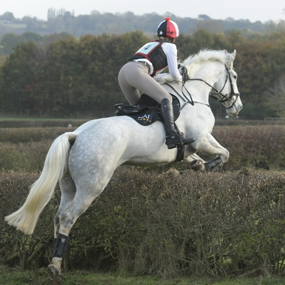 Woman riding a horse in a cross country competition wearing the Mountain Horse Diana Breeches in Grey