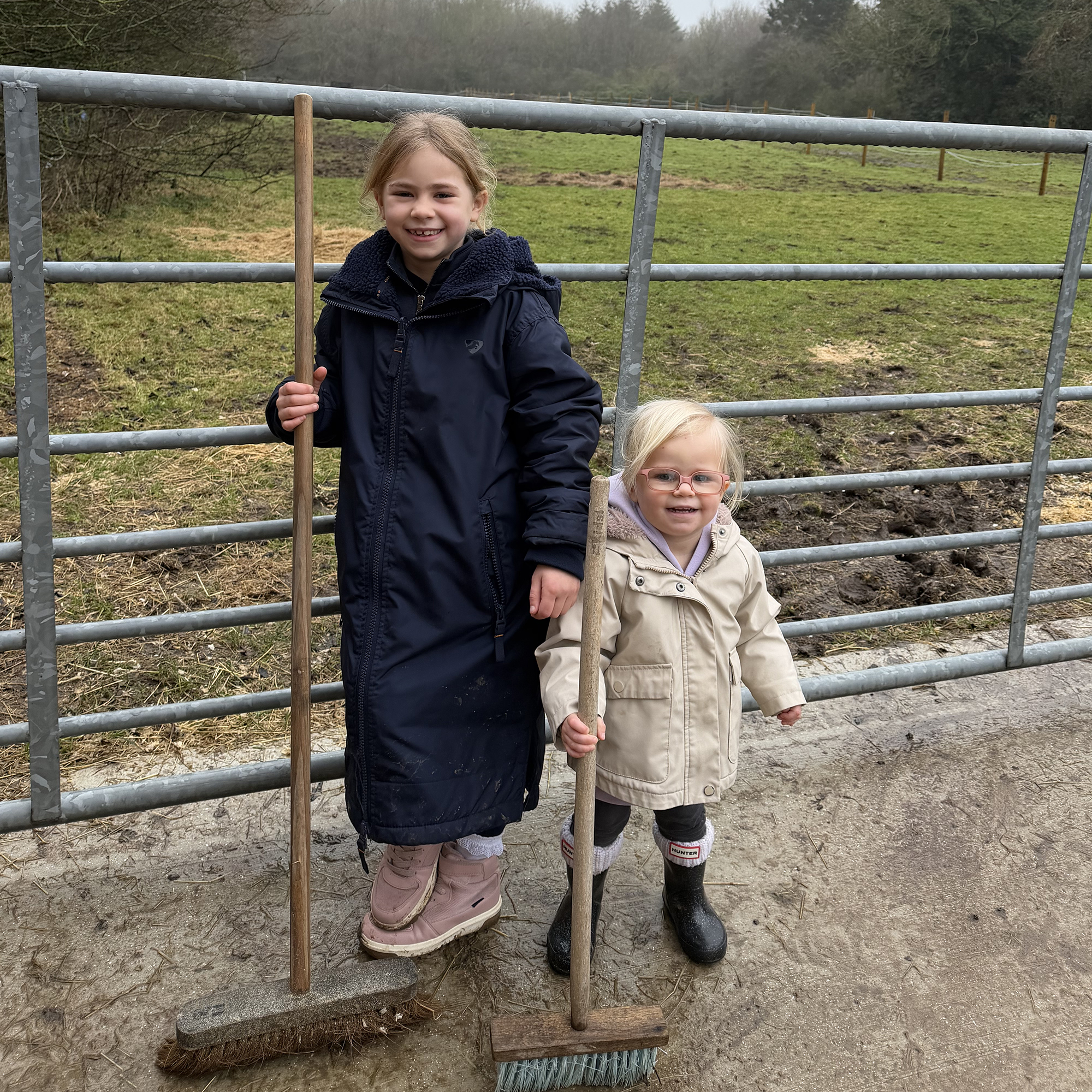 Two children doing stable jobs, one wearing the Kids Aubrion All Weather Robe