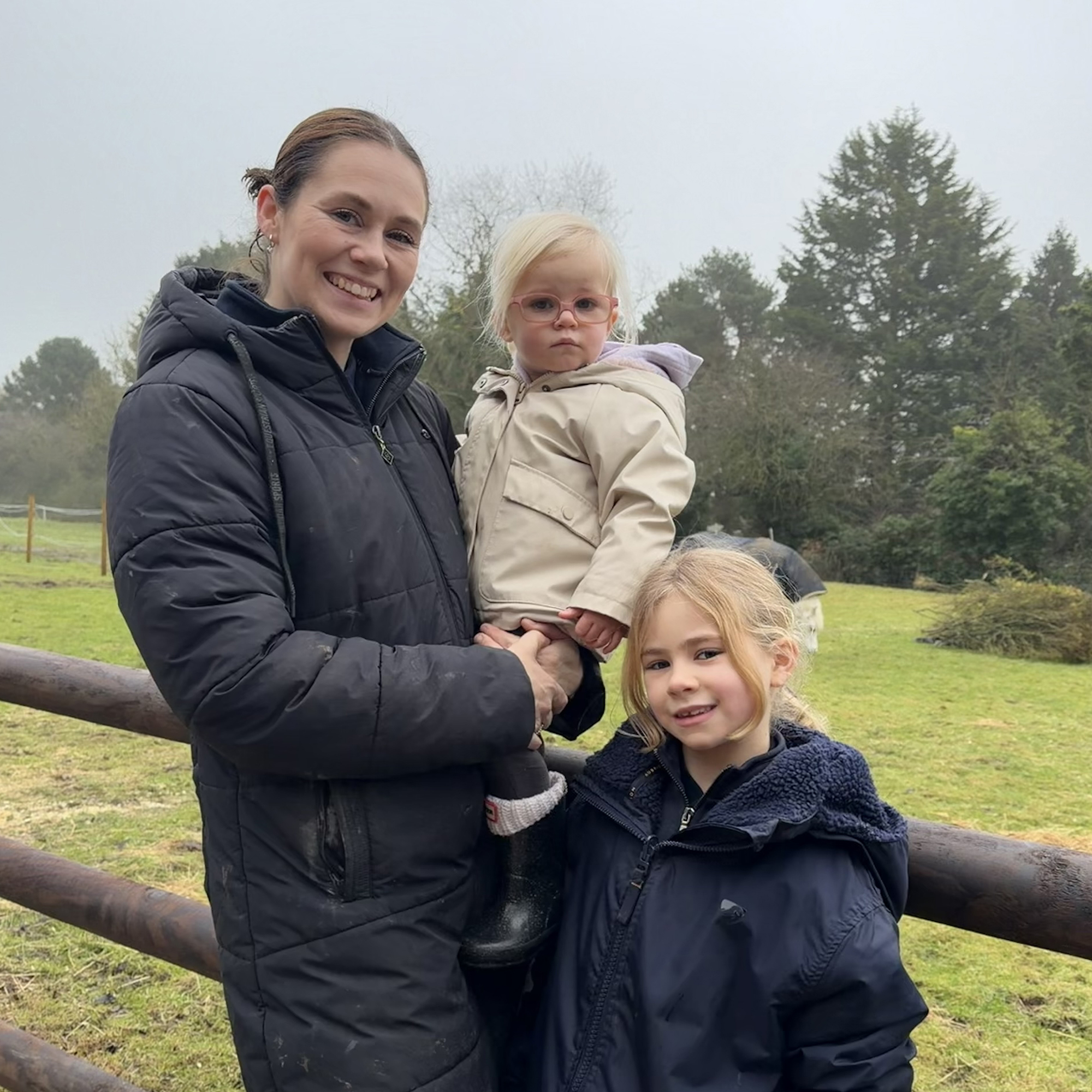 Equestrian family of mum and two daughters outside overlooking field
