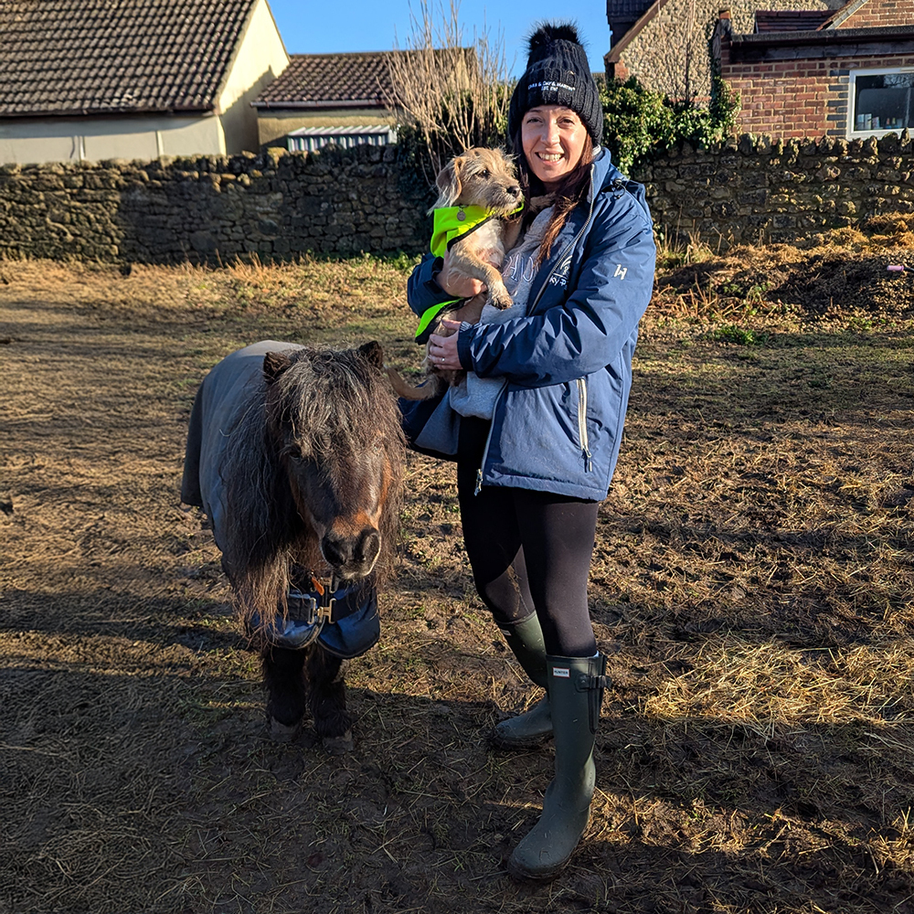 Woman wearing Ladies Hunter wellies in field holding a dog next to a shetland pony