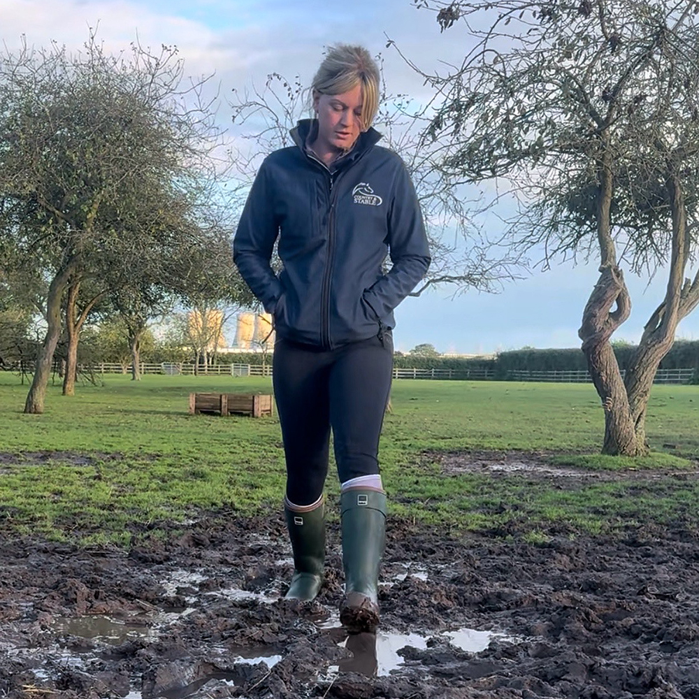 Woman walking in muddy field wearing Toggi Barnsdale Wellies