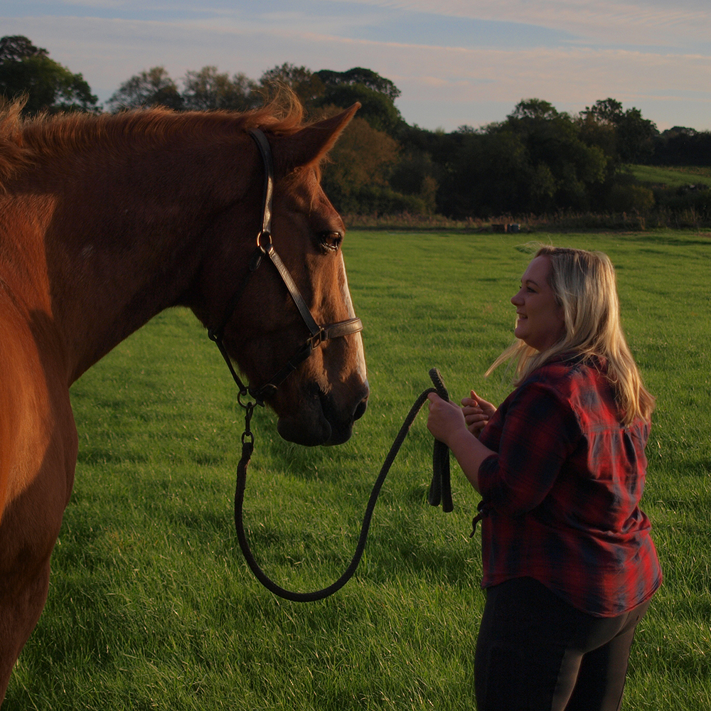 Woman saying goodby to her horse in a field