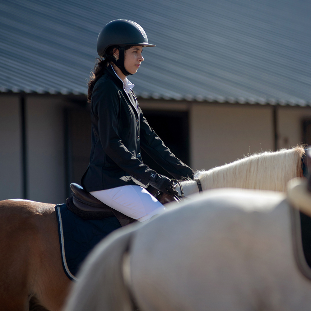 Young horse rider at local show preparing for show jumping class